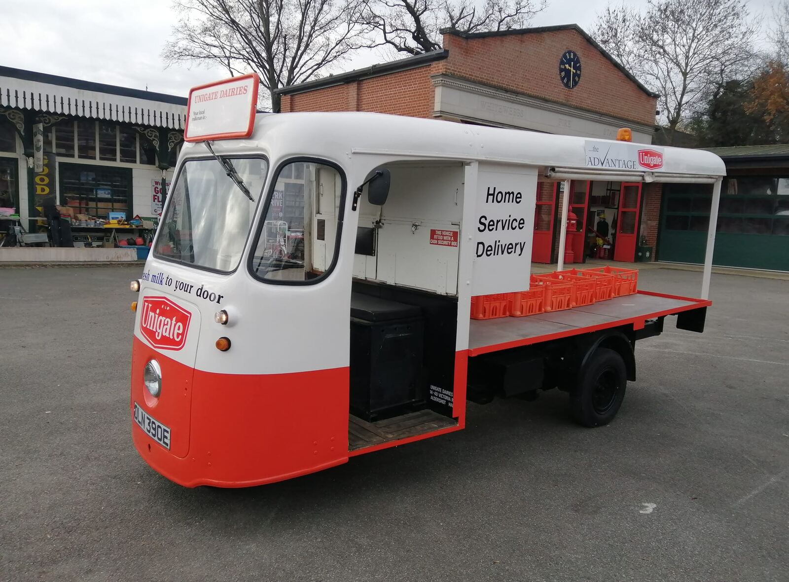 A red and white Unigate Dairies milk float with 'Home Service Delivery' on the side.